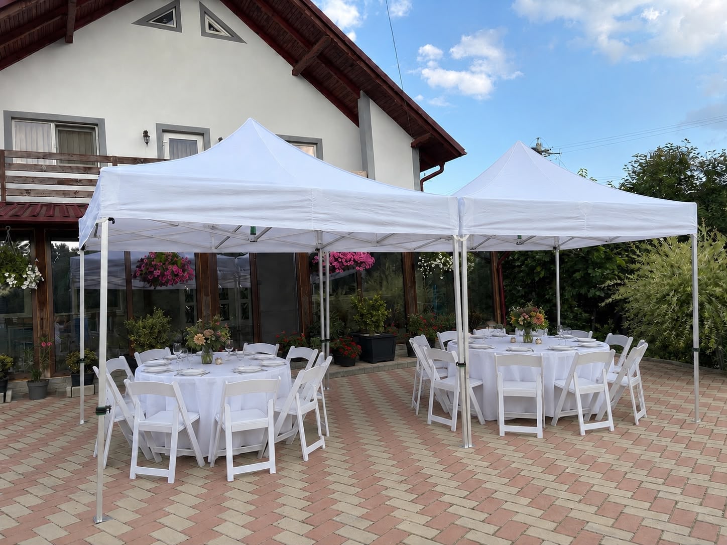 Două corturi albe cu mese rotunde și scaune albe pentru eveniment
